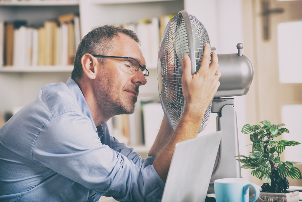 man holding a fan close to his face