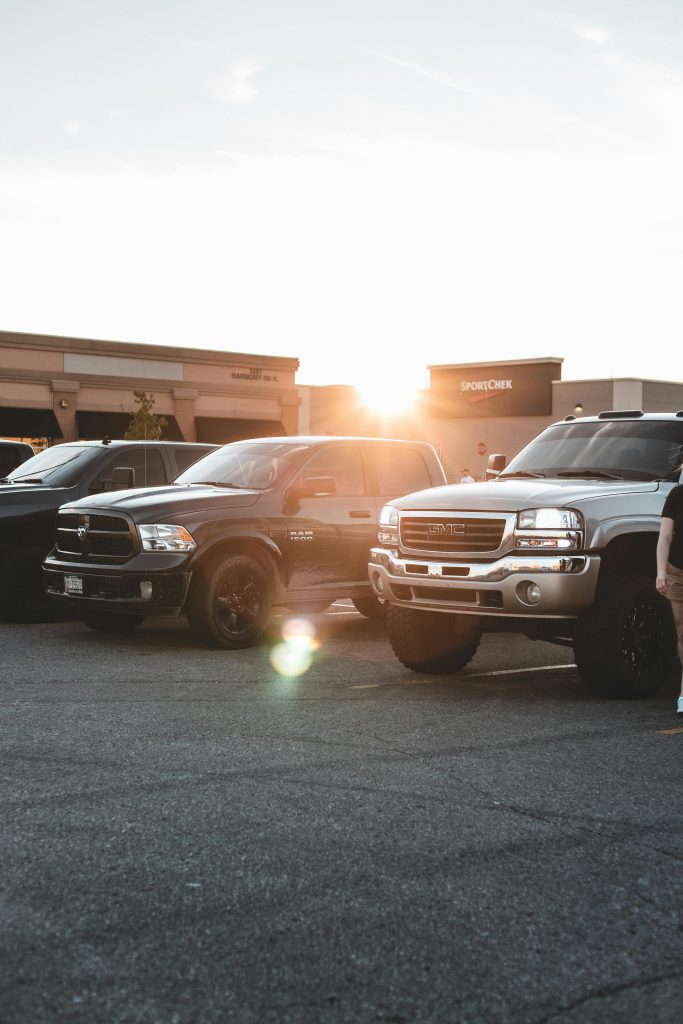 pexels-photo-7395259-7395259 A row of pickup trucks parked at sunset in a parking lot, showcasing modern vehicle design.
